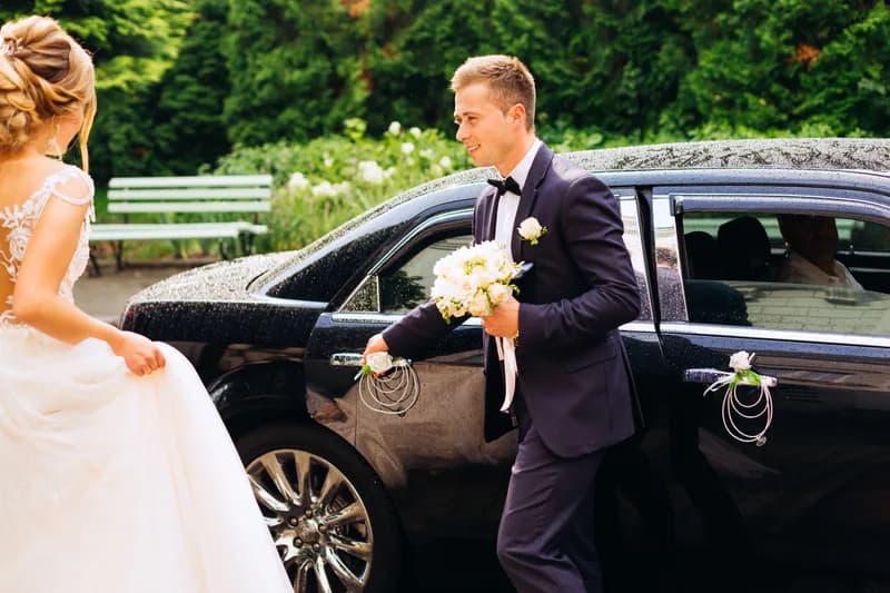 A groom beside a black luxury sedan