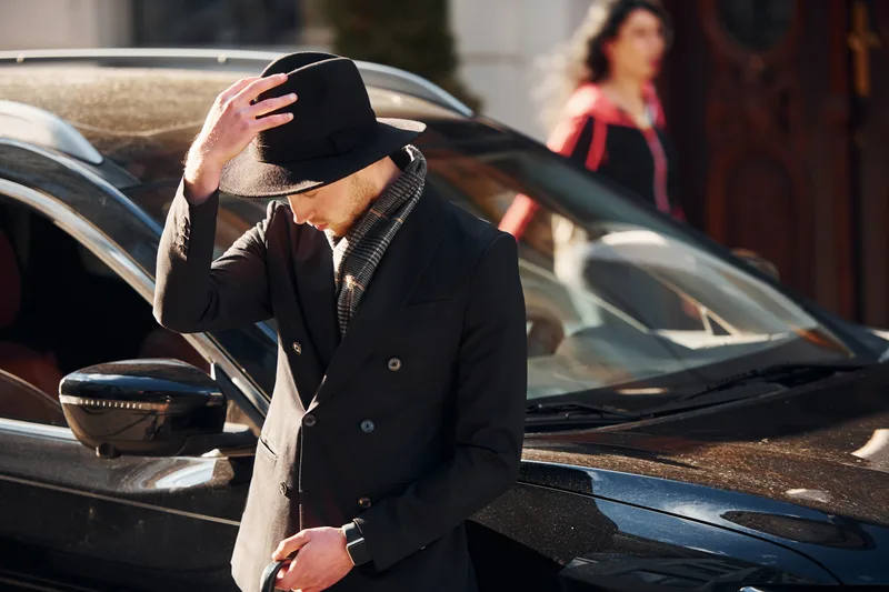 A chauffeur waiting beside a black car