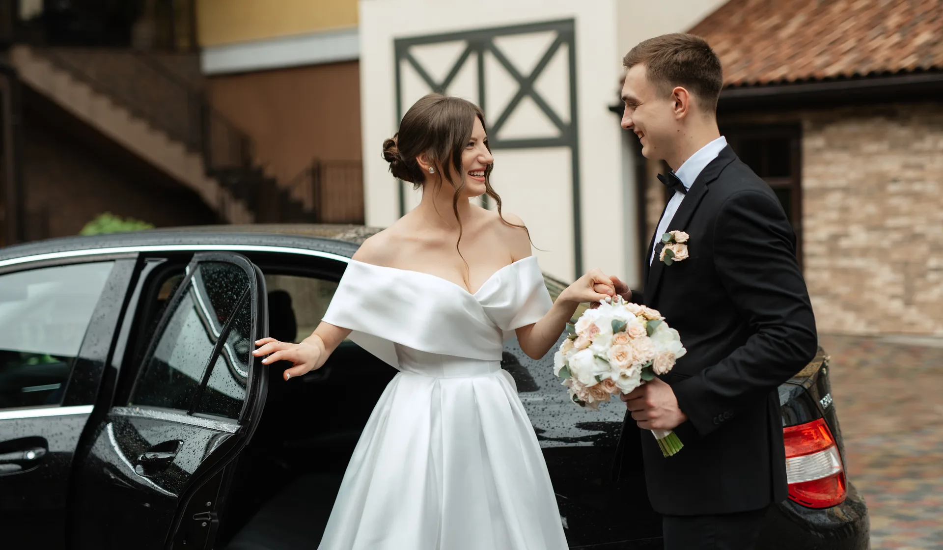 A newly married couple beside their luxury wedding car