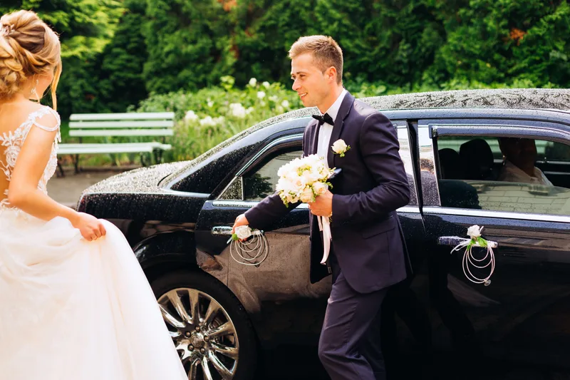 A groom beside a black luxury sedan