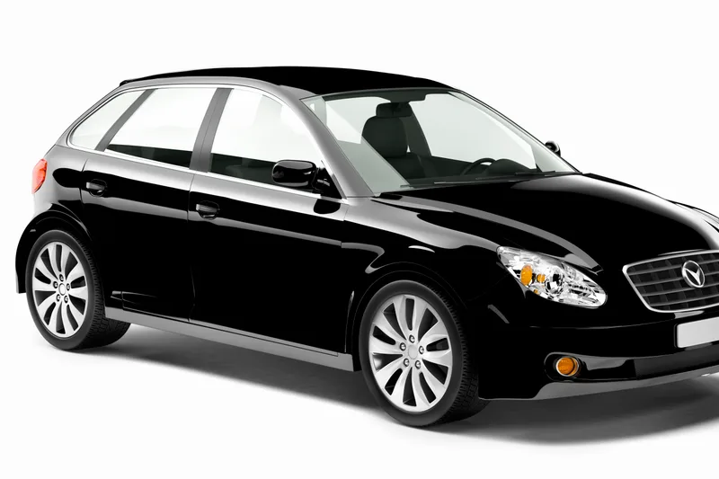 A chauffeured black sedan waiting for a passenger outside airport arrivals
