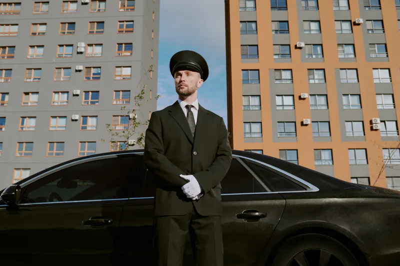 A chauffeur waiting beside a luxury car in the city