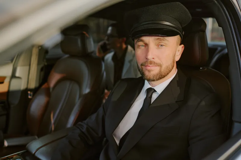 A professional chauffeur driving a business passenger through the city