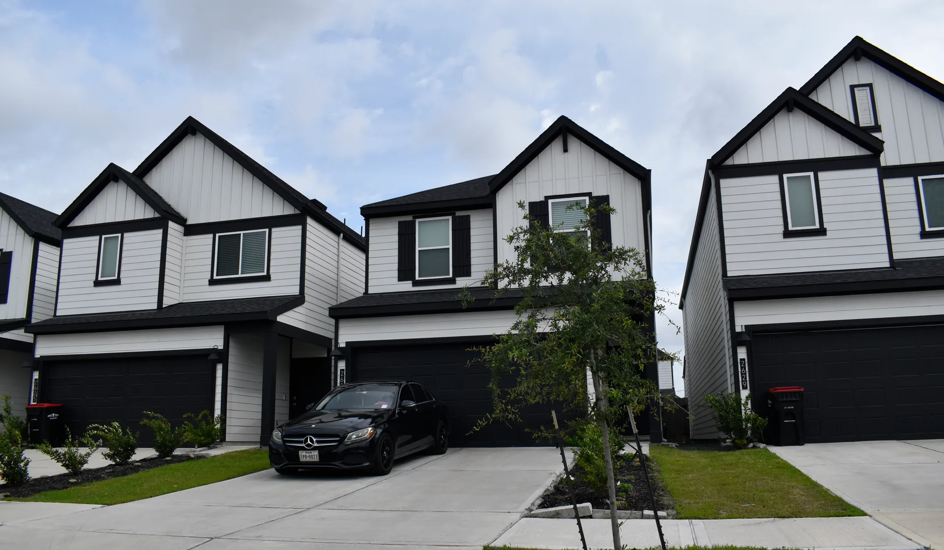 A black luxury sedan parked outside an upscale home