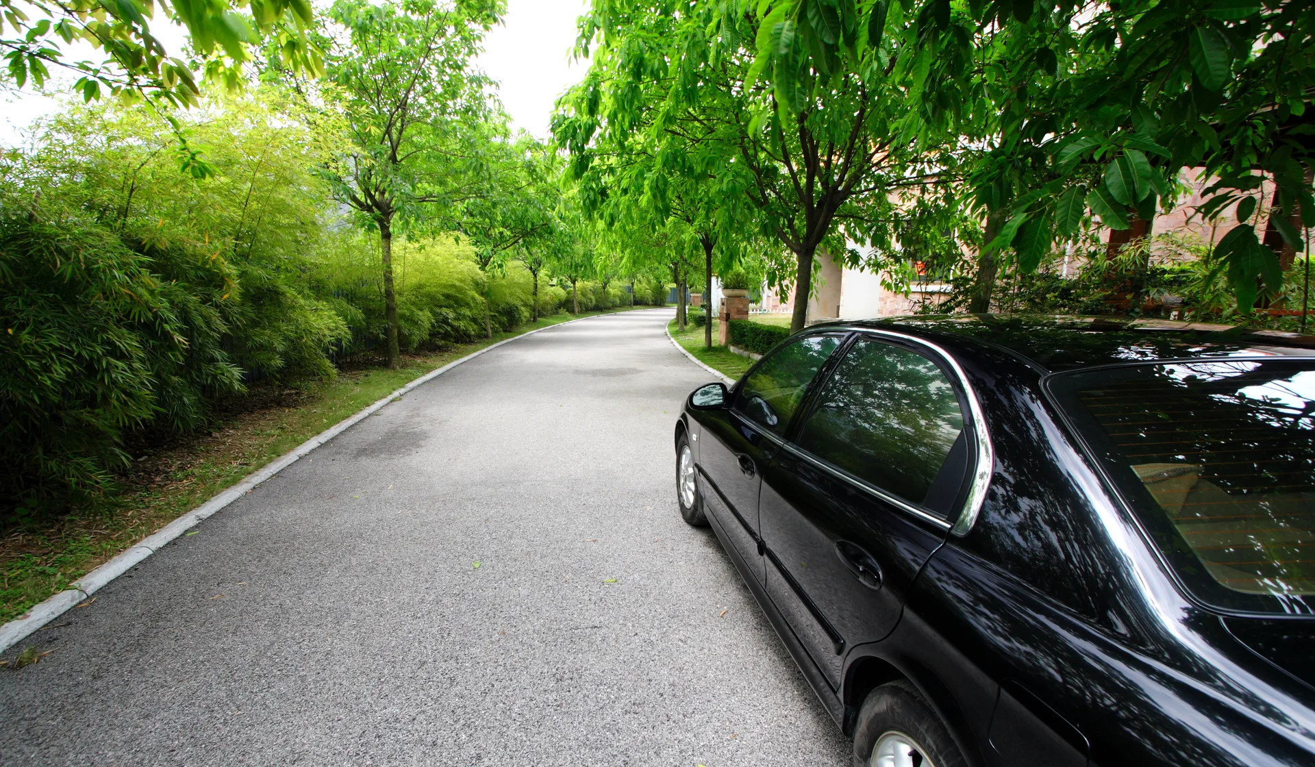 A luxury car on a leafy street in an affluent lakeside town